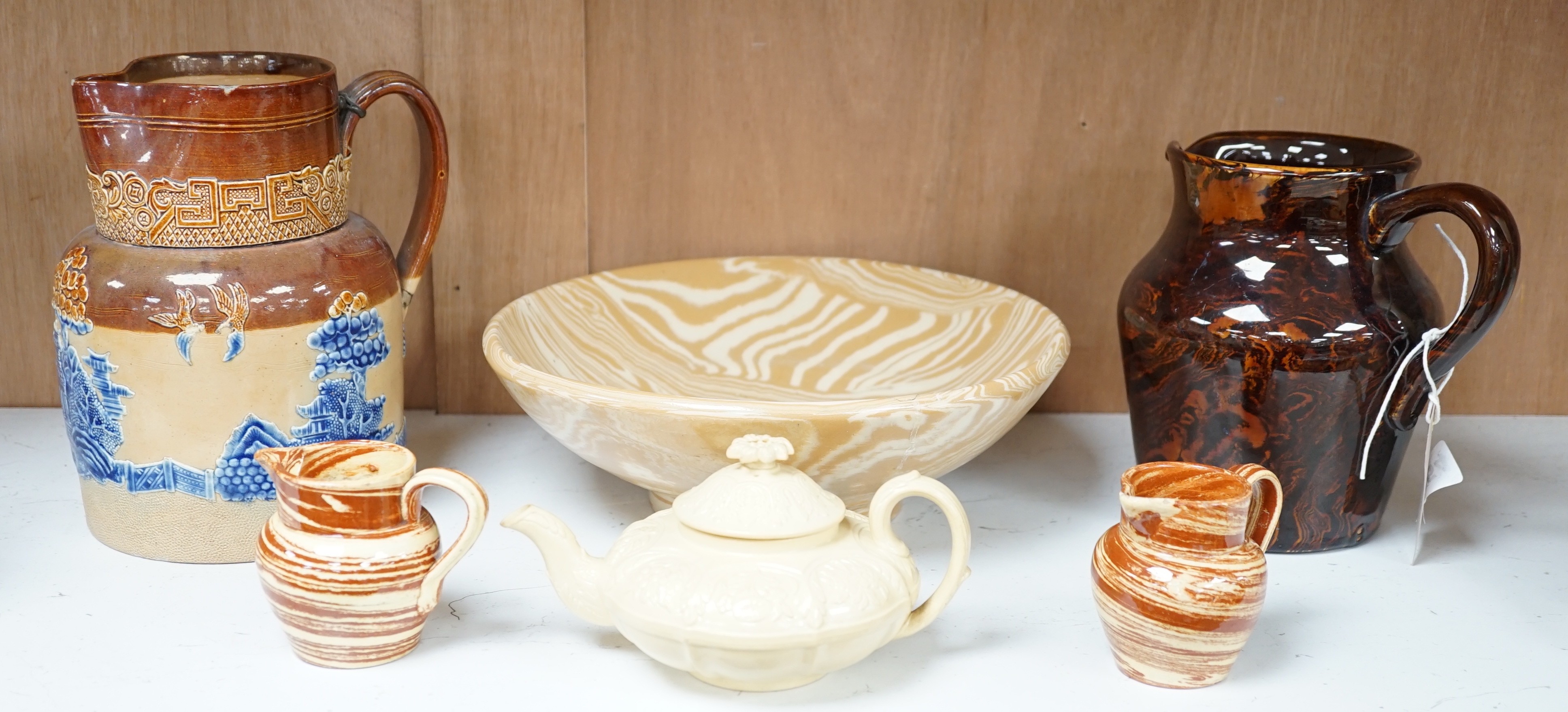 A Victorian solid agate ware pottery jug, a similar bowl and pair of miniature jugs, an unusual Doulton Lambeth stoneware jug and a small relief-moulded teapot, Doulton jug, 19cms high